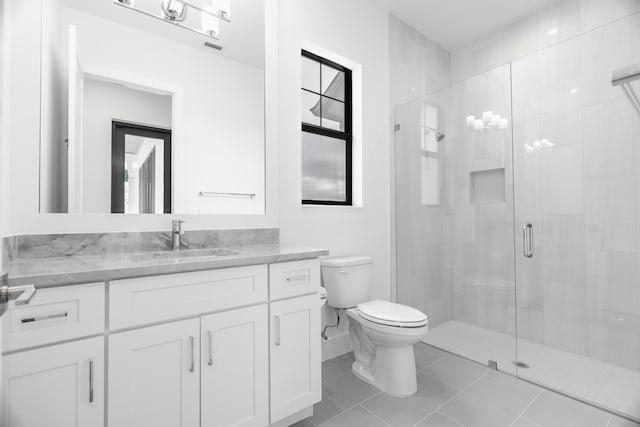 bathroom featuring toilet, vanity, tile patterned floors, and a shower with door