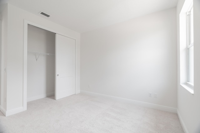 unfurnished bedroom featuring a closet and light carpet