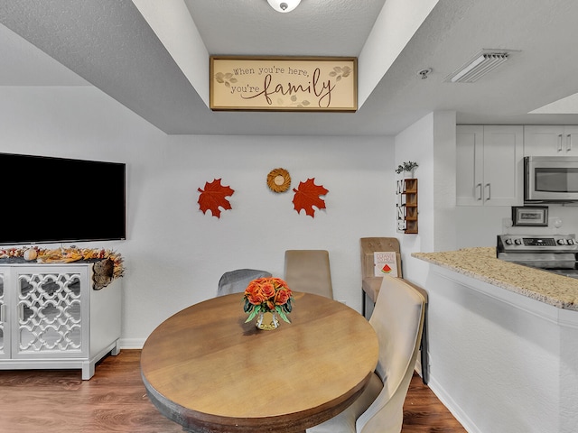 dining room with hardwood / wood-style floors and a textured ceiling