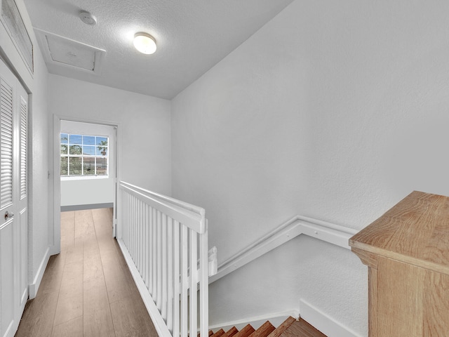 corridor with a textured ceiling and dark hardwood / wood-style flooring