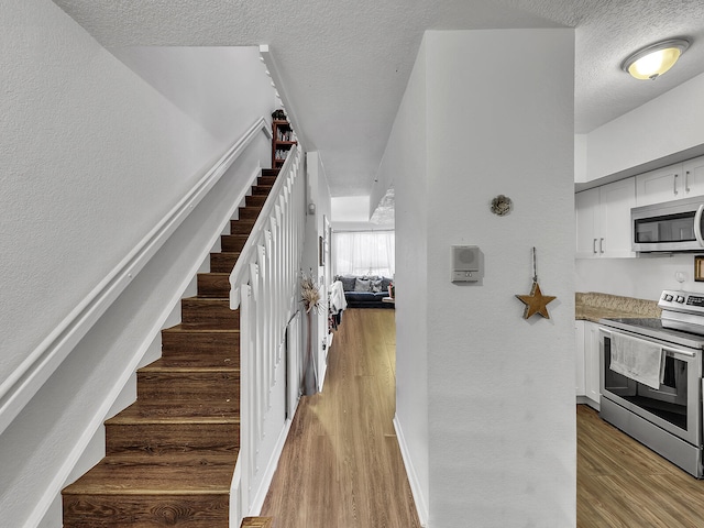 stairway featuring hardwood / wood-style floors and a textured ceiling