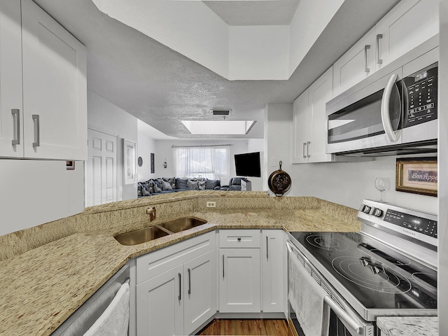 kitchen with light stone countertops, appliances with stainless steel finishes, sink, and white cabinets