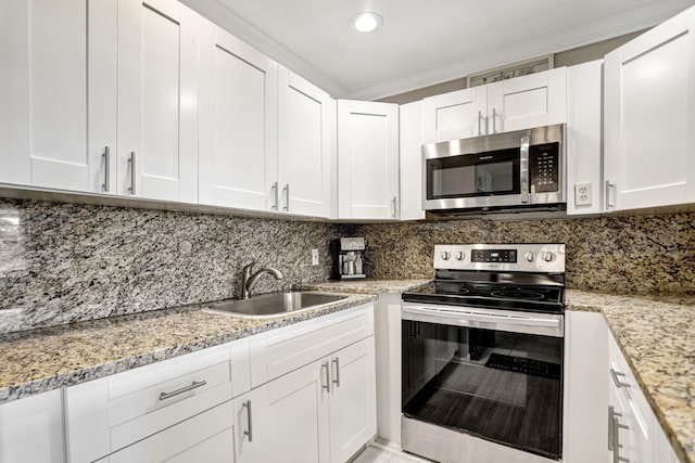 kitchen featuring stainless steel appliances, light stone countertops, sink, and white cabinets