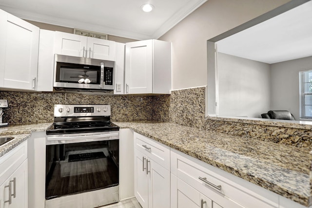 kitchen with decorative backsplash, stainless steel appliances, ornamental molding, light stone countertops, and white cabinetry