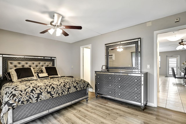 bedroom featuring a wall mounted AC, hardwood / wood-style flooring, and ceiling fan