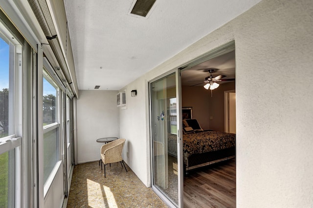 sunroom / solarium with an AC wall unit and ceiling fan