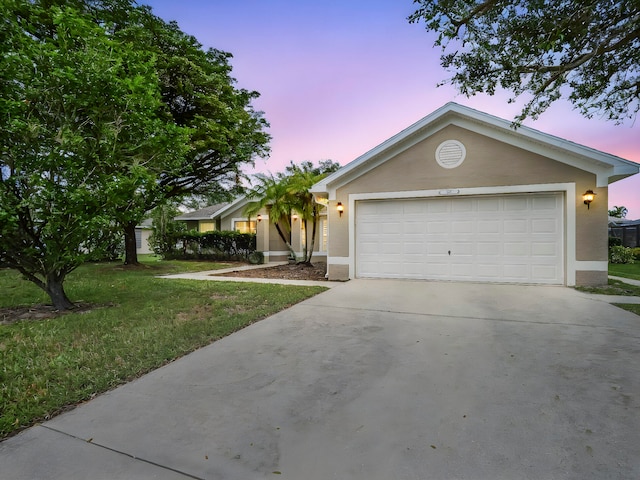 ranch-style house with a garage and a lawn