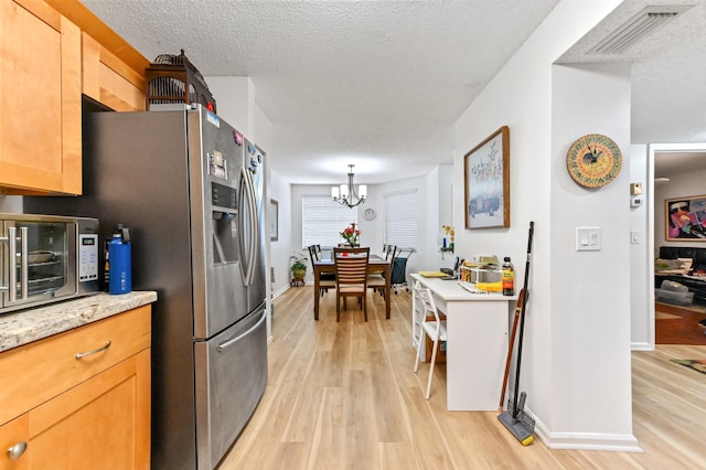 kitchen with a notable chandelier, hanging light fixtures, a textured ceiling, and light hardwood / wood-style floors