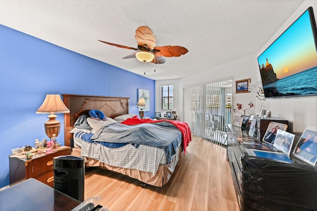 bedroom featuring a textured ceiling, wood-type flooring, access to outside, and ceiling fan