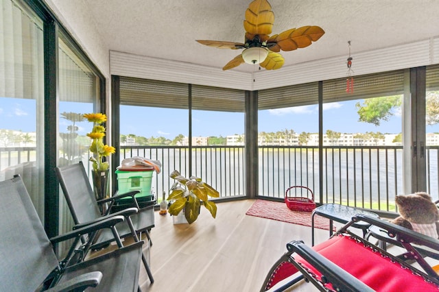 sunroom featuring a water view and ceiling fan