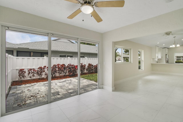 interior space featuring plenty of natural light and ceiling fan with notable chandelier