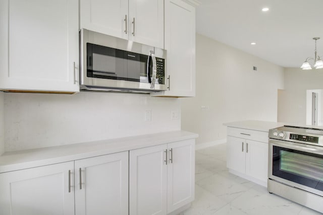 kitchen with pendant lighting, appliances with stainless steel finishes, a chandelier, and white cabinets