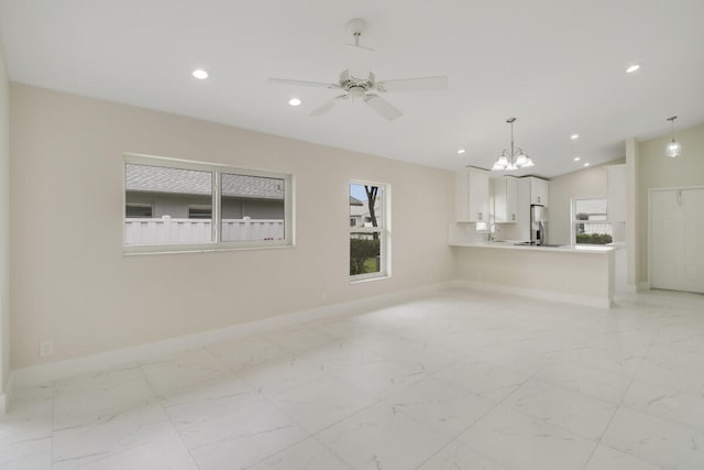 unfurnished living room with lofted ceiling and ceiling fan with notable chandelier