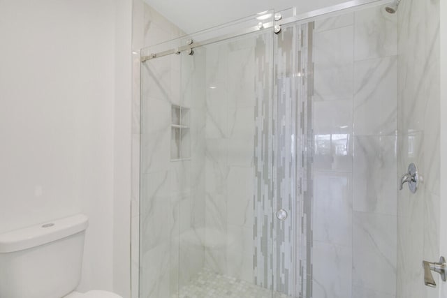 bathroom featuring toilet and a shower with shower door