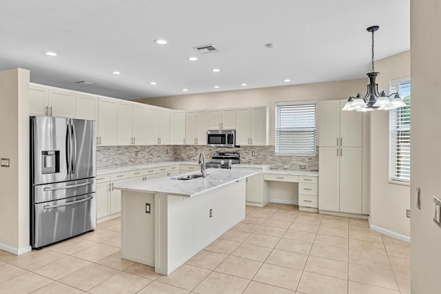 kitchen with appliances with stainless steel finishes, sink, plenty of natural light, and an island with sink