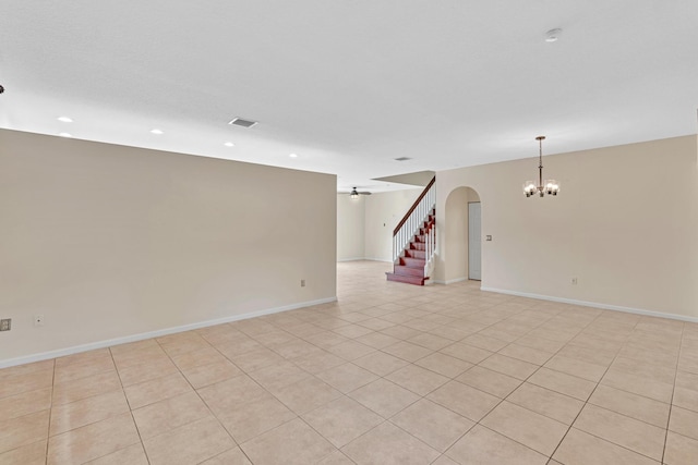 spare room featuring light tile patterned flooring and ceiling fan with notable chandelier