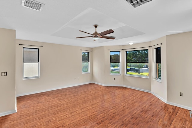 unfurnished room with light hardwood / wood-style flooring, a raised ceiling, and ceiling fan