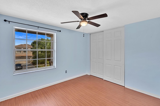 unfurnished bedroom featuring a textured ceiling, hardwood / wood-style flooring, a closet, and ceiling fan