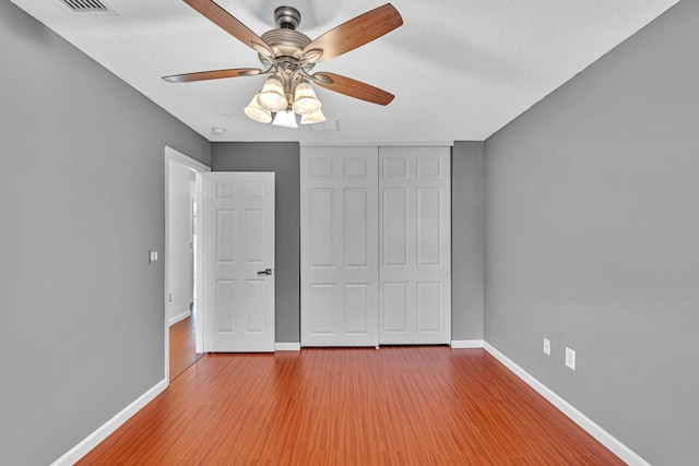 unfurnished bedroom with a closet, hardwood / wood-style floors, a textured ceiling, and ceiling fan