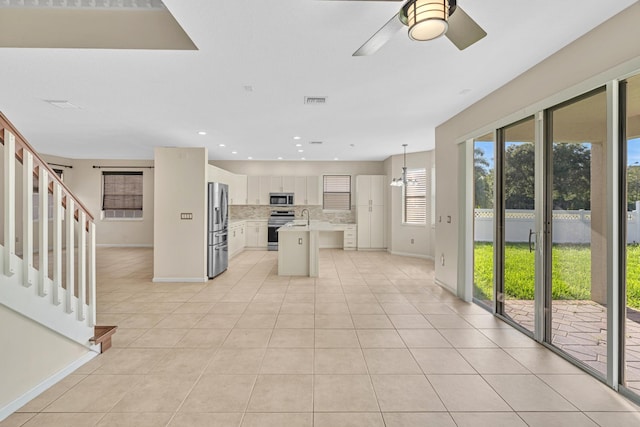 kitchen with decorative backsplash, light tile patterned floors, stainless steel appliances, pendant lighting, and a center island