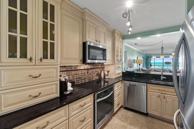2571 NE Ocean Blvd Unit 10-203, Stuart, FL 34996 - kitchen featuring cream cabinetry, appliances with stainless steel finishes, a sink, ornamental molding, and backsplash