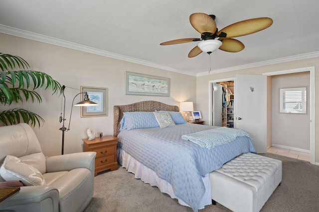 bedroom with ceiling fan, ornamental molding, a closet, a walk in closet, and light colored carpet