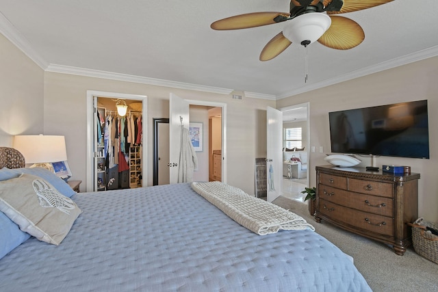 bedroom featuring ceiling fan, ornamental molding, a closet, a walk in closet, and light colored carpet