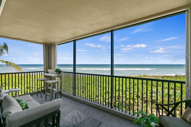 sunroom featuring a water view and a beach view