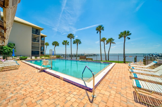 view of pool featuring a water view and a patio