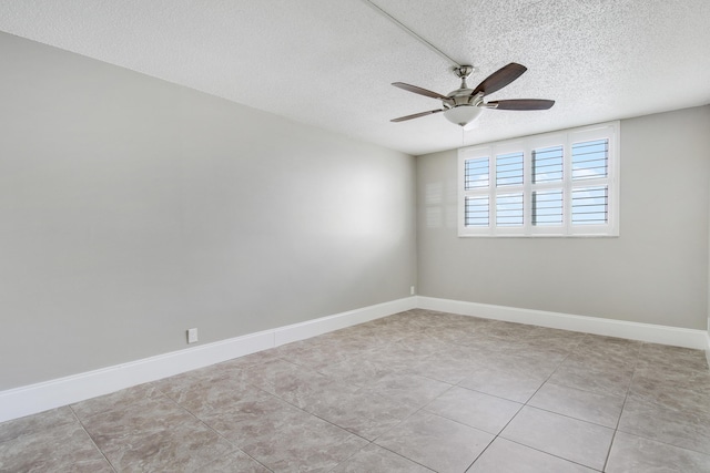 unfurnished room featuring a ceiling fan, light tile patterned floors, baseboards, and a textured ceiling