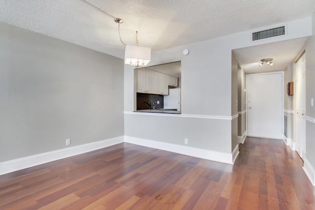 unfurnished living room featuring hardwood / wood-style floors, a notable chandelier, and a textured ceiling