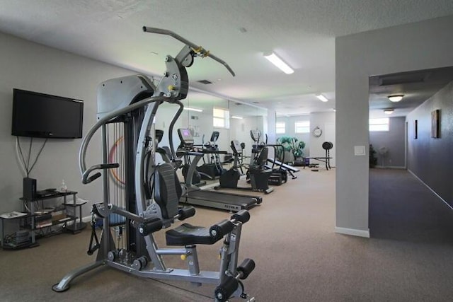 exercise room featuring a textured ceiling and baseboards