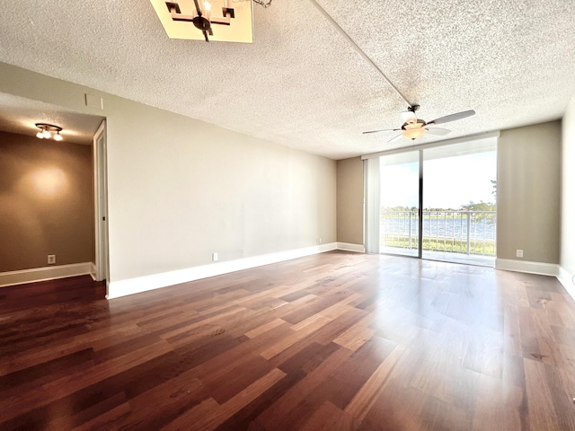 empty room featuring expansive windows, wood finished floors, and baseboards