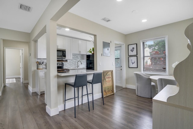 kitchen with dark wood-type flooring, tasteful backsplash, stainless steel appliances, and white cabinets