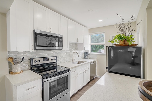 kitchen featuring white cabinets, decorative backsplash, stainless steel appliances, and sink