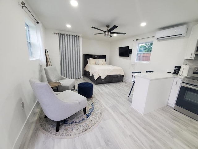 bedroom with a wall unit AC, ceiling fan, and light hardwood / wood-style flooring