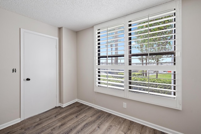 unfurnished room with a healthy amount of sunlight, a textured ceiling, and hardwood / wood-style floors