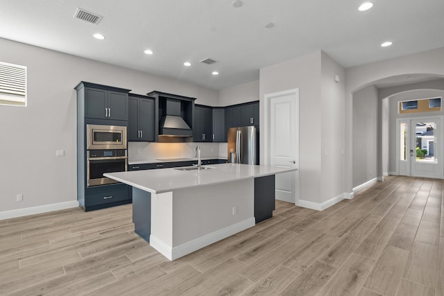 12501 SW Sunrise Lake Ter, Port Saint Lucie, FL 34987 - kitchen with stainless steel appliances, custom exhaust hood, arched walkways, a sink, and light countertops