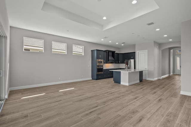 12501 SW Sunrise Lake Ter, Port Saint Lucie, FL 34987 - kitchen with arched walkways, stainless steel appliances, a tray ceiling, light countertops, and open floor plan