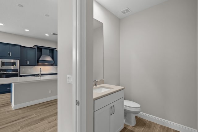12501 SW Sunrise Lake Ter, Port Saint Lucie, FL 34987 - bathroom with wood finished floors, vanity, toilet, baseboards, and recessed lighting