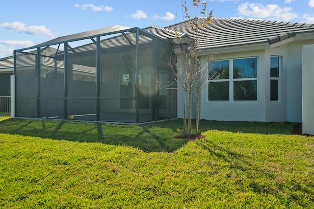 12501 SW Sunrise Lake Ter, Port Saint Lucie, FL 34987 - back of property with a yard, stucco siding, a tile roof, and glass enclosure