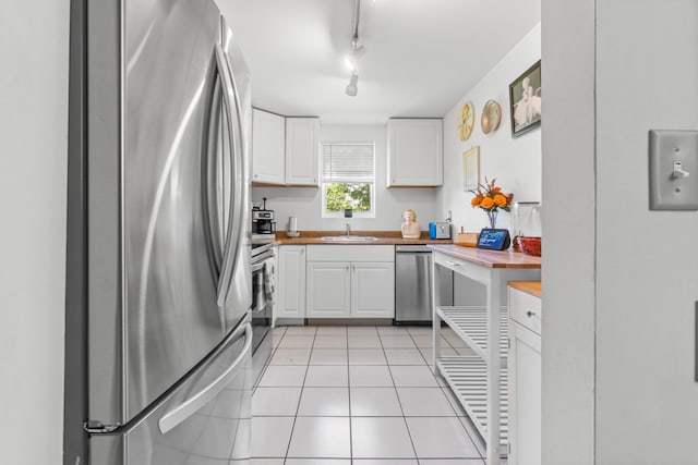 kitchen featuring appliances with stainless steel finishes, white cabinets, butcher block counters, and track lighting