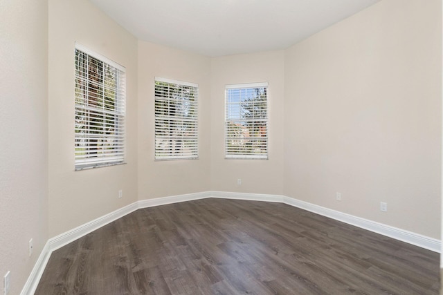 spare room featuring dark wood-type flooring and a healthy amount of sunlight