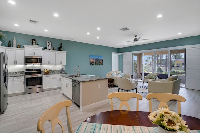 kitchen with white cabinets, a kitchen island with sink, light stone countertops, sink, and stainless steel appliances