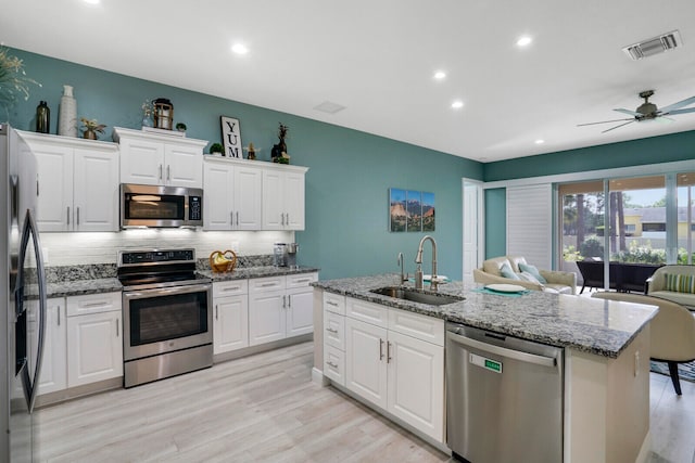 kitchen featuring a kitchen island with sink, sink, white cabinets, and stainless steel appliances