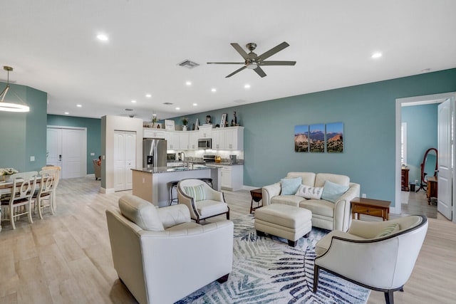 living room featuring light hardwood / wood-style flooring and ceiling fan