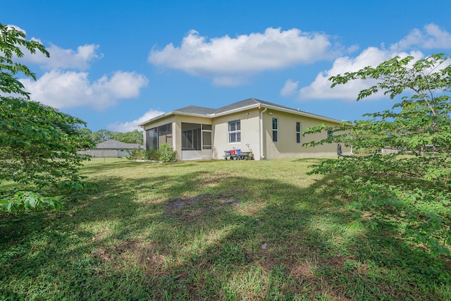 back of house with a sunroom and a lawn