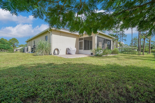 back of property with a yard, a sunroom, and a patio area