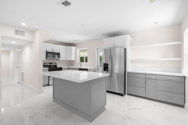 kitchen featuring sink, a kitchen island, white cabinets, and stainless steel appliances