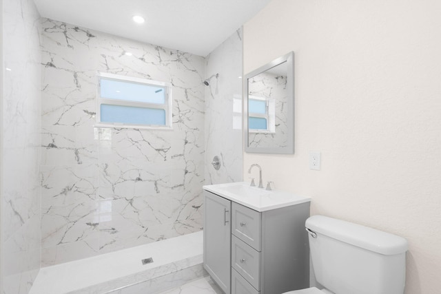 bathroom featuring vanity, toilet, and tiled shower